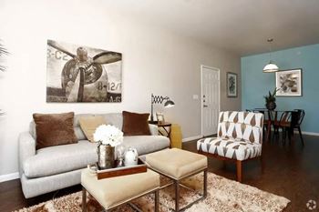 A living room with a couch, chair, and a painting of a bird on the wall.